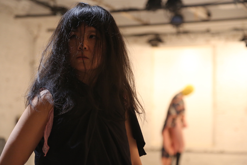 A woman stares ahead of her. Her shoulder length black hair covers her face.